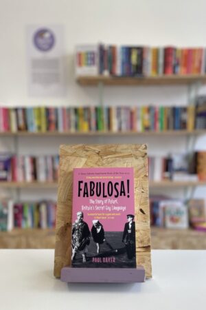 Copi o 'Fabulosa' yn sefyll ar stondin llyfrau, tu blaen silffoedd o lyfrau yn y cefndir.