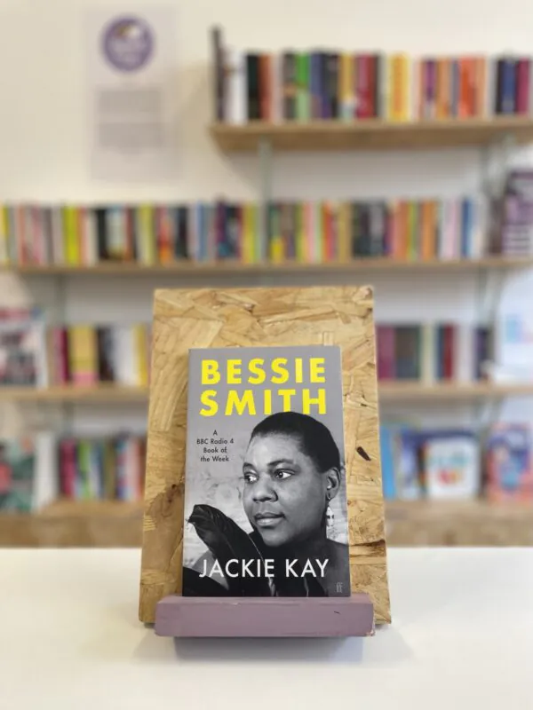 Copi o 'Bessie Smith' yn sefyll ar stondin llyfrau, tu blaen silffoedd o lyfrau yn y cefndir.